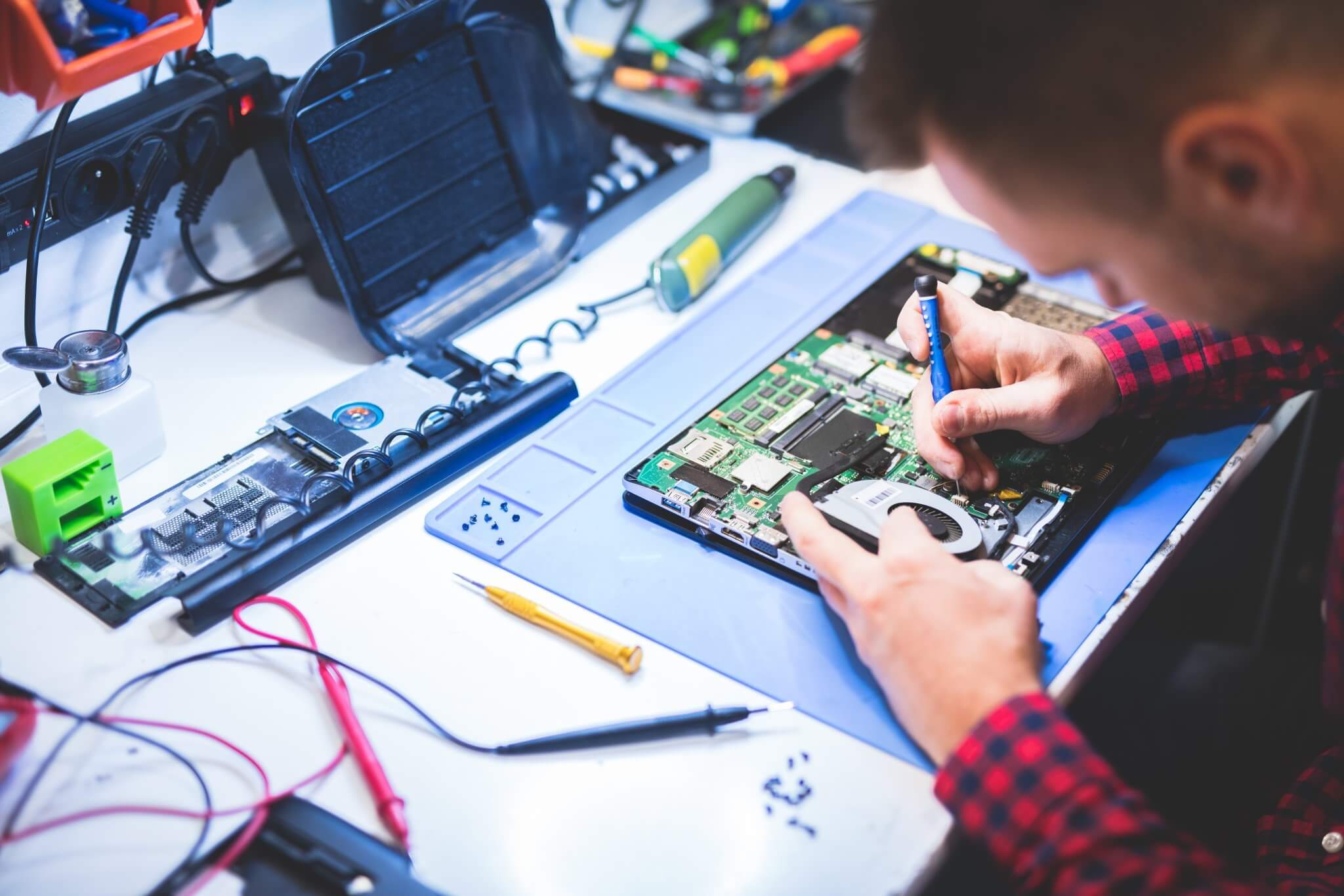 Technician repairing an overheating laptop, fan visible